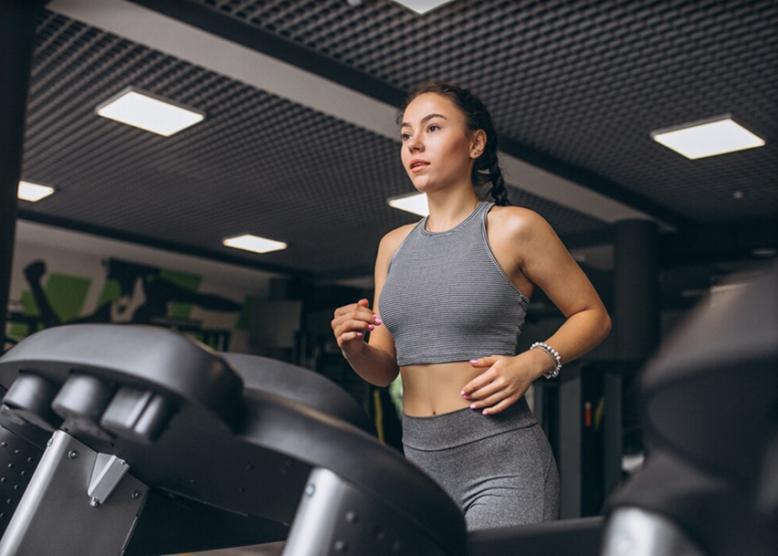 Девушка на электро беговой дорожке в фитнес-клубе